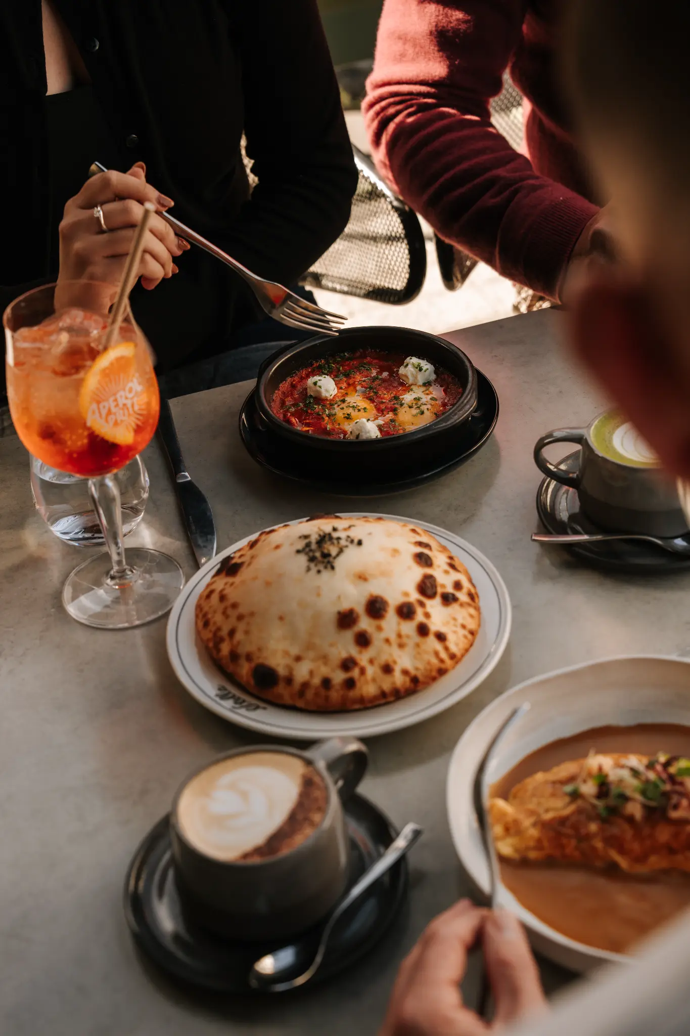 Guests enjoying eggs, flatbread, coffee and a spritz at Stella brunch