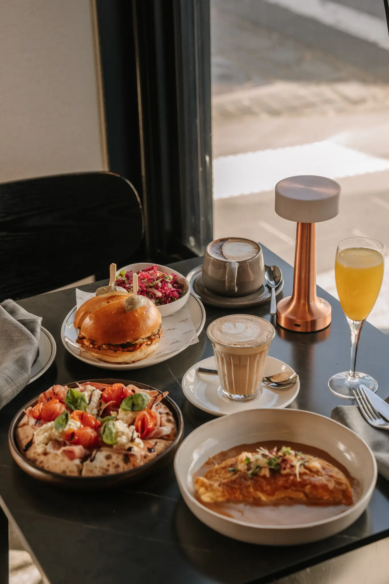 A Stella brunch table with coffee, eggs, pizza and a spritz